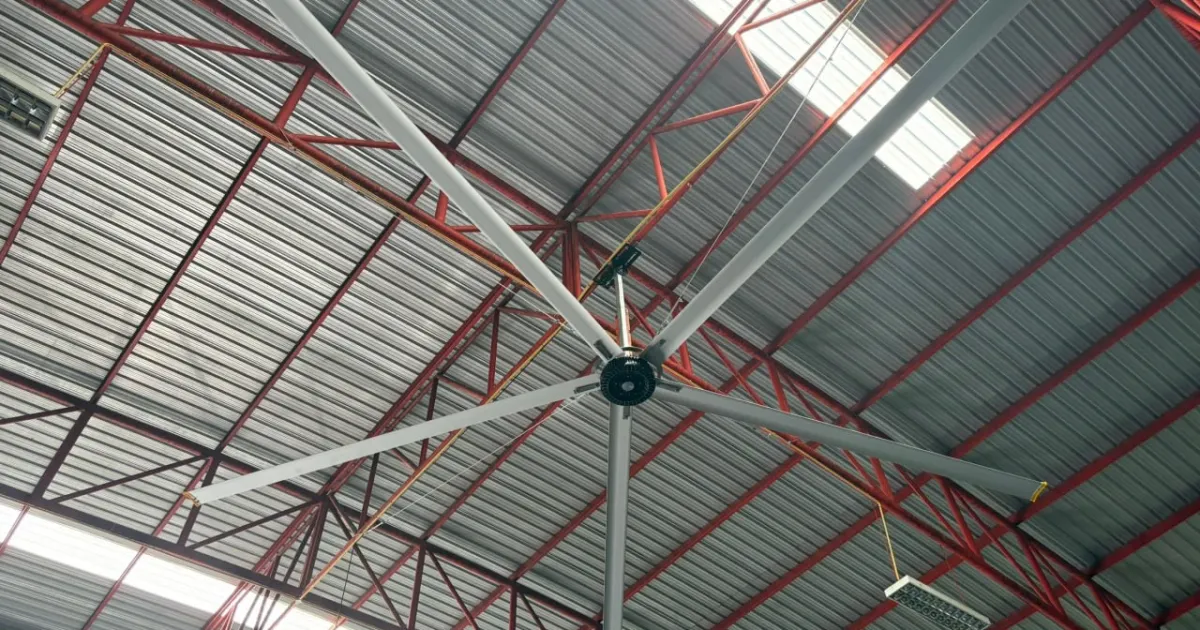 พัดลมยักษ์ HVLS Mactech ใต้หลังคาโครงถักเหล็กในโกดัง