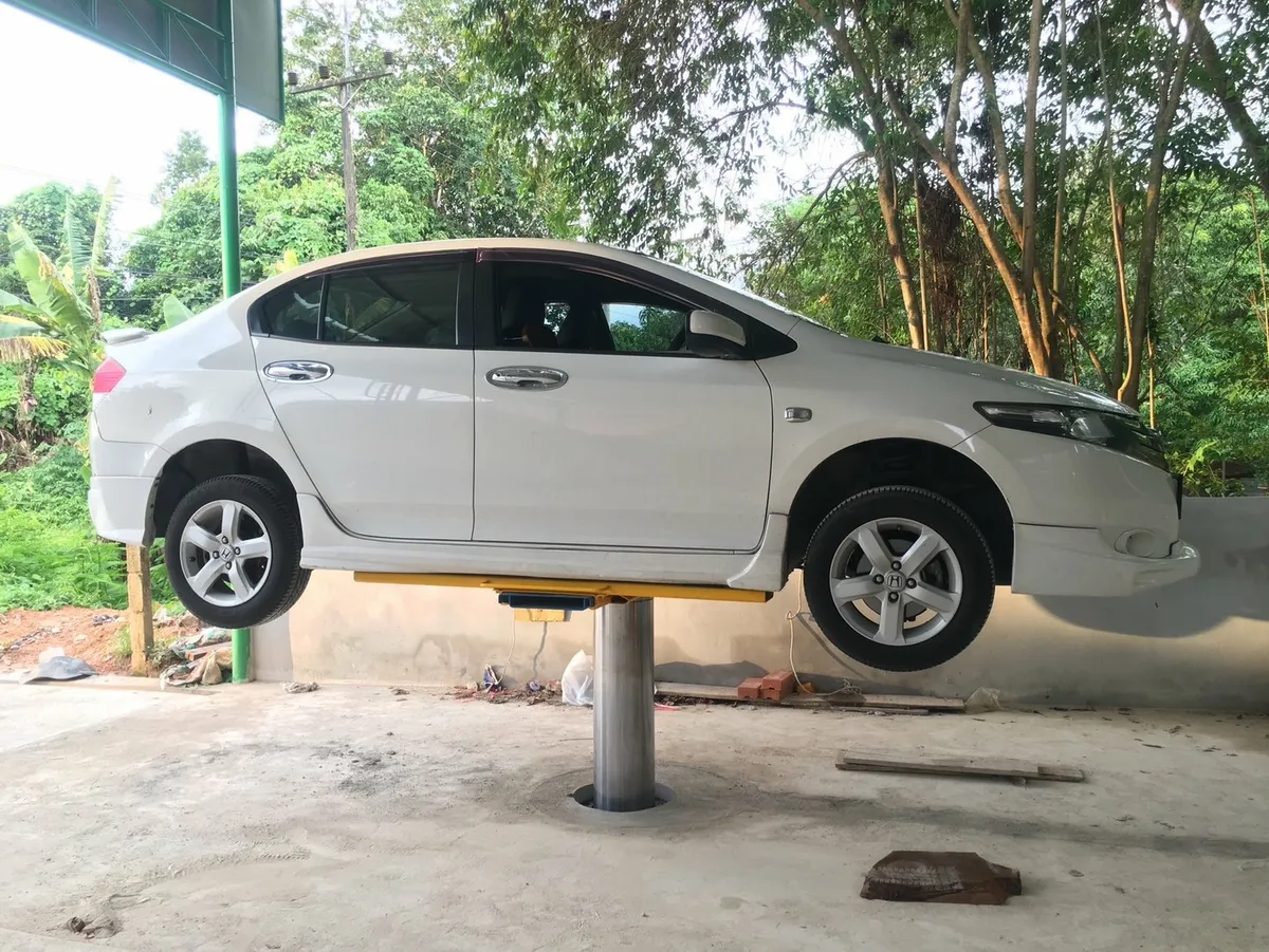 รถเก๋งสีขาวยกขึ้นบนลิฟท์เสาเดียวในร้านล้างรถ