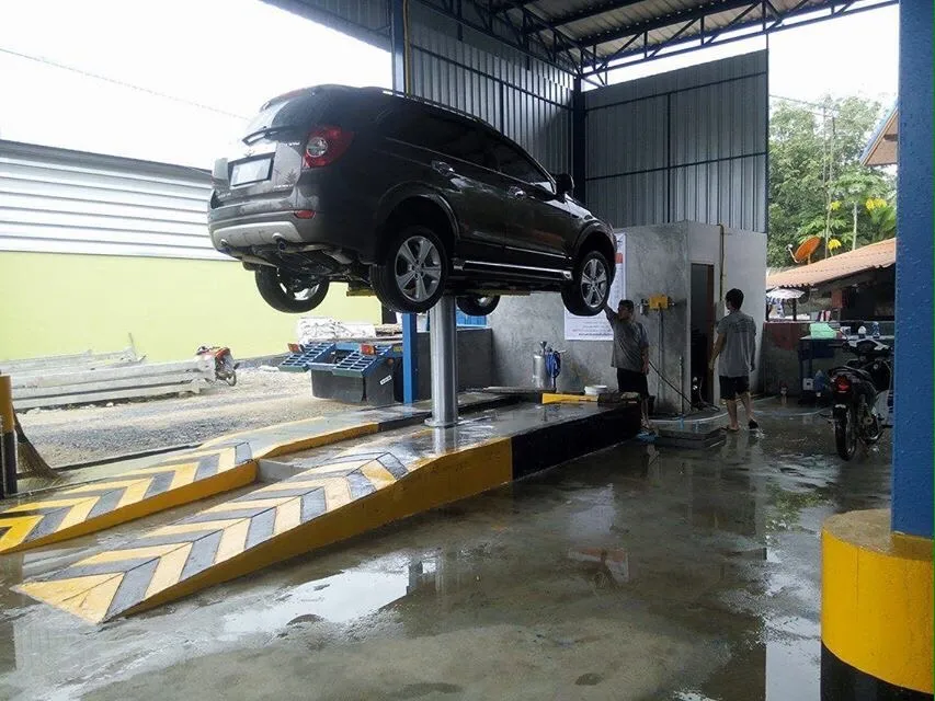 รถ SUV สีดำยกบนลิฟท์เสาเดียว พร้อมทางลาดลายเหลืองดำสองข้าง