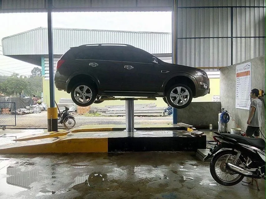 รถ SUV ยกบนลิฟท์เสาเดียวในช่องล้างที่มีขอบทางสีดำเหลือง