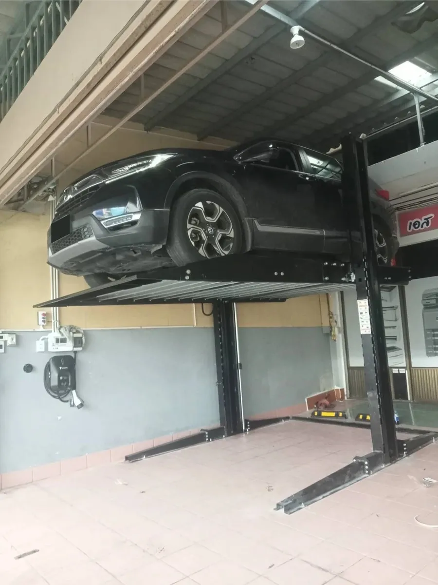 รถ SUV สีดำอยู่บนแท่นลิฟท์จอดรถ 2 เสาที่ยกขึ้น