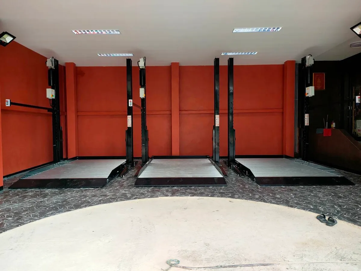 ลิฟท์จอดรถ 2 เสาติดตั้งเรียง 3 ชุดในโรงรถผนังสีส้ม